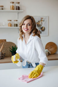 Housewife in yellow gloves wipes the kitchen table