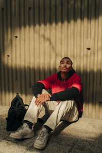 Thoughtful young man sitting against wall