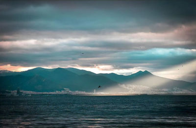 Scenic view of sea and mountains against sky