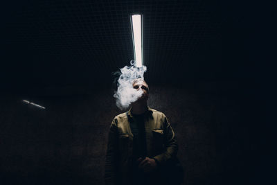 Portrait of man smoking cigarette against black background