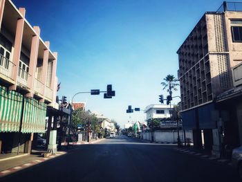 Road amidst buildings against blue sky