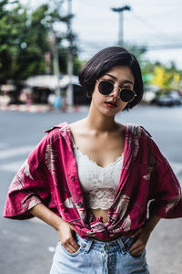 Portrait of sensuous woman wearing sunglasses while standing on road