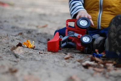 Low section of man with toy sitting on sand