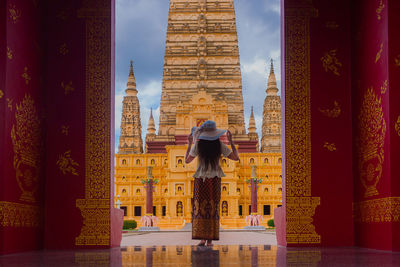 Rear view of woman wearing hat standing against religious building