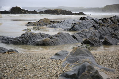 Scenic view of rocks on beach against sky