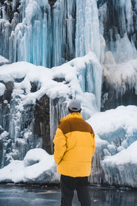 Rear view of woman standing against waterfall