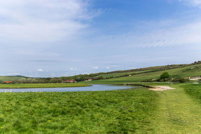 Scenic view of grassy field against cloudy sky