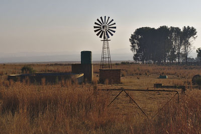 Traditional windmill on field against sky during sunset