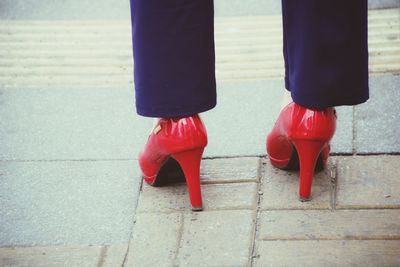 Low section of woman standing on footpath