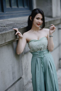 Portrait of young woman standing against wall