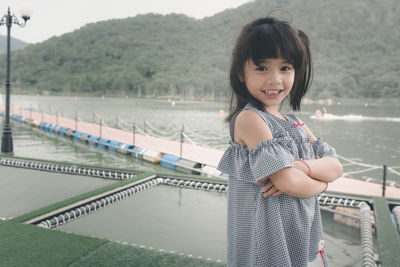 Portrait of smiling girl standing against water