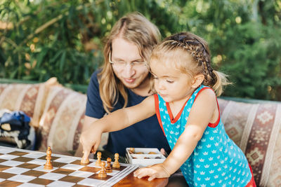 Girl playing chess with father