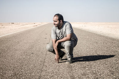 Full length of man sitting on road