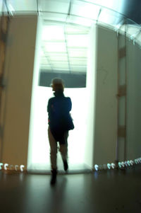 Rear view of man walking in corridor of building