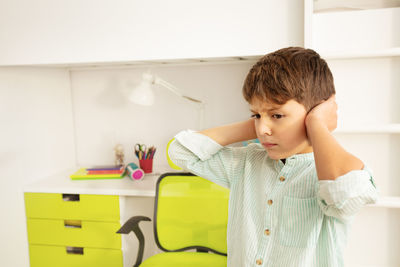 Boy closing ears at school