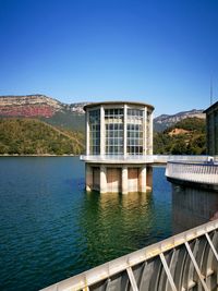 Building by lake against clear blue sky