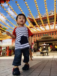 Portrait of cute boy in amusement park against sky