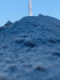 Close-up of snow covered land against clear blue sky