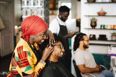 Female barber giving head massage to male customer in hair salon