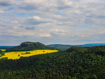 Scenic view of agricultural field against cloudy sky