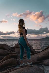 Full length of man standing on rock at beach against sky