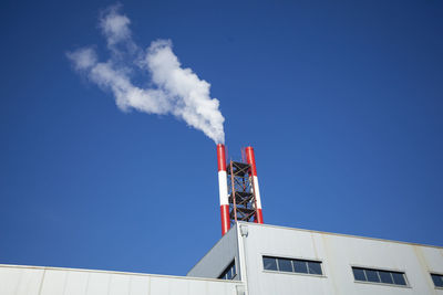 Low angle view of smoke emitting from chimney against sky