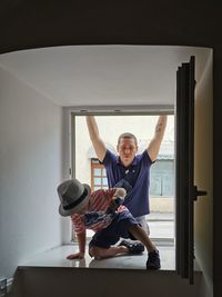 Father standing by window  while son kneeling on floor