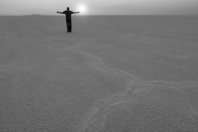 Silhouette man with arms outstretched standing at beach