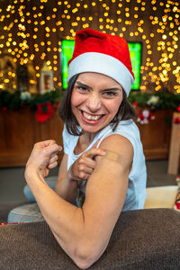 Portrait of a young female smiling after getting a vaccine - woman showing arm during a christmas