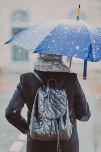 Rear view of woman with umbrella in snowfall 