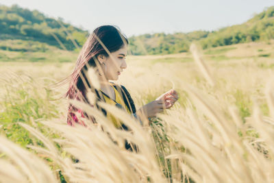 Young woman using mobile phone in field