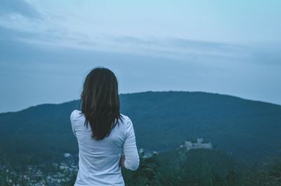 Rear view of woman standing on mountain against sky