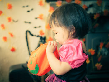 Close-up of cute girl holding orange purse at home