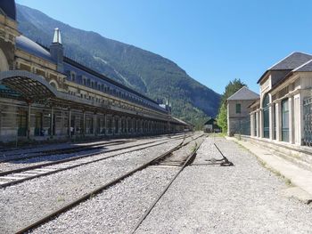 Railroad tracks by buildings against clear sky