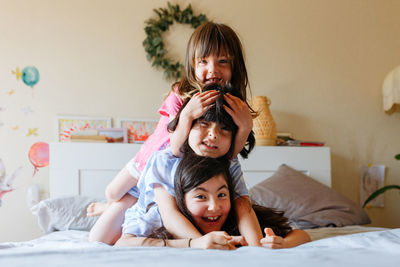 Pyramid of three smiling girls lying on each other