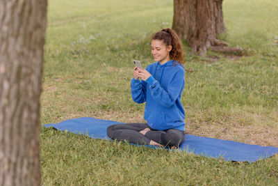 Side view of young woman sitting on field