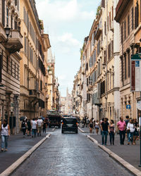 People on road amidst buildings against sky