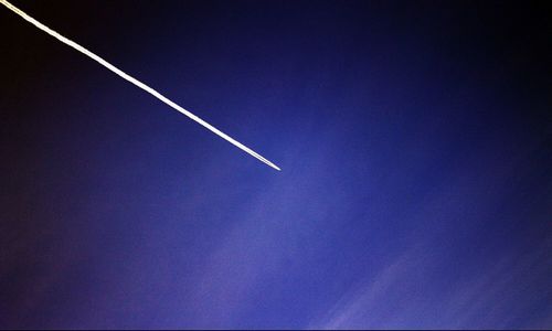 Low angle view of vapor trails against blue sky