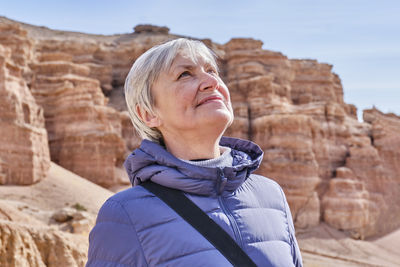 Senior woman looking up over background of rocks of charyn canyon, kazakhstan.