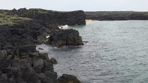 Rock formations by sea against sky