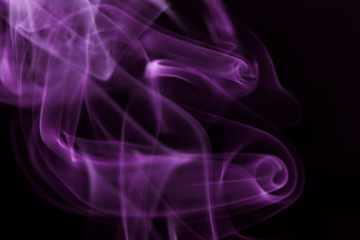 Close-up of purple smoke pattern against black background