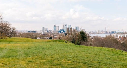 Field by city against sky