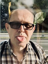 Close-up portrait of mature man sticking out tongue while standing on road
