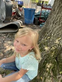 Portrait of smiling young woman sitting on tree trunk