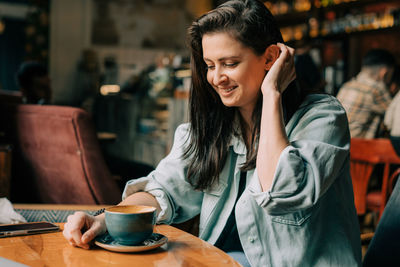 Beautiful laughing happy brunette woman drinking coffee in a coffee shop.