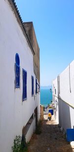Houses by sea against clear blue sky