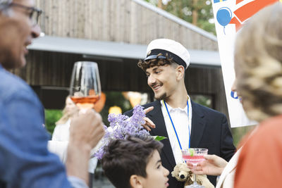 Smiling young man wearing cap standing amidst family at back yard