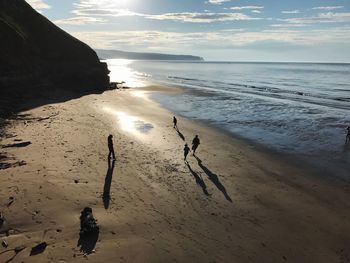 High angle view of people at beach against sky during sunset