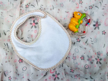 High angle view of baby bib and toy on fabric