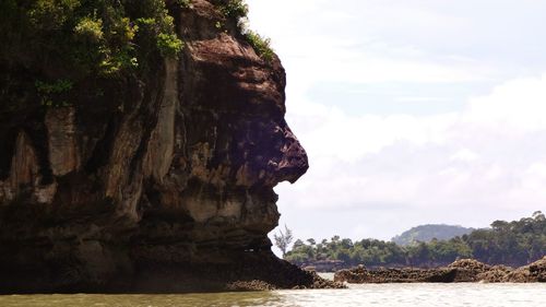 Large rock in sea against sky